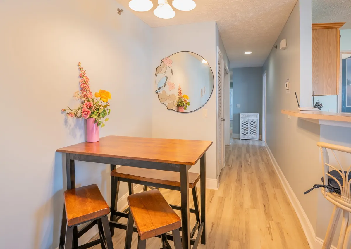 A warm and welcoming entryway scene with a wooden table, floral arrangement, and a round mirror, evoking a cozy atmosphere as you enter the home.