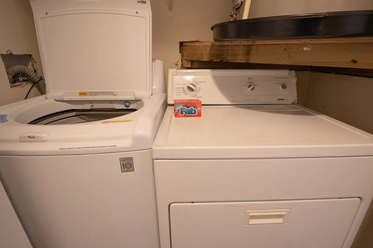 A straightforward shot of a laundry closet featuring a washing machine, dryer, and a detergent box, emphasizing the in-unit laundry amenities.