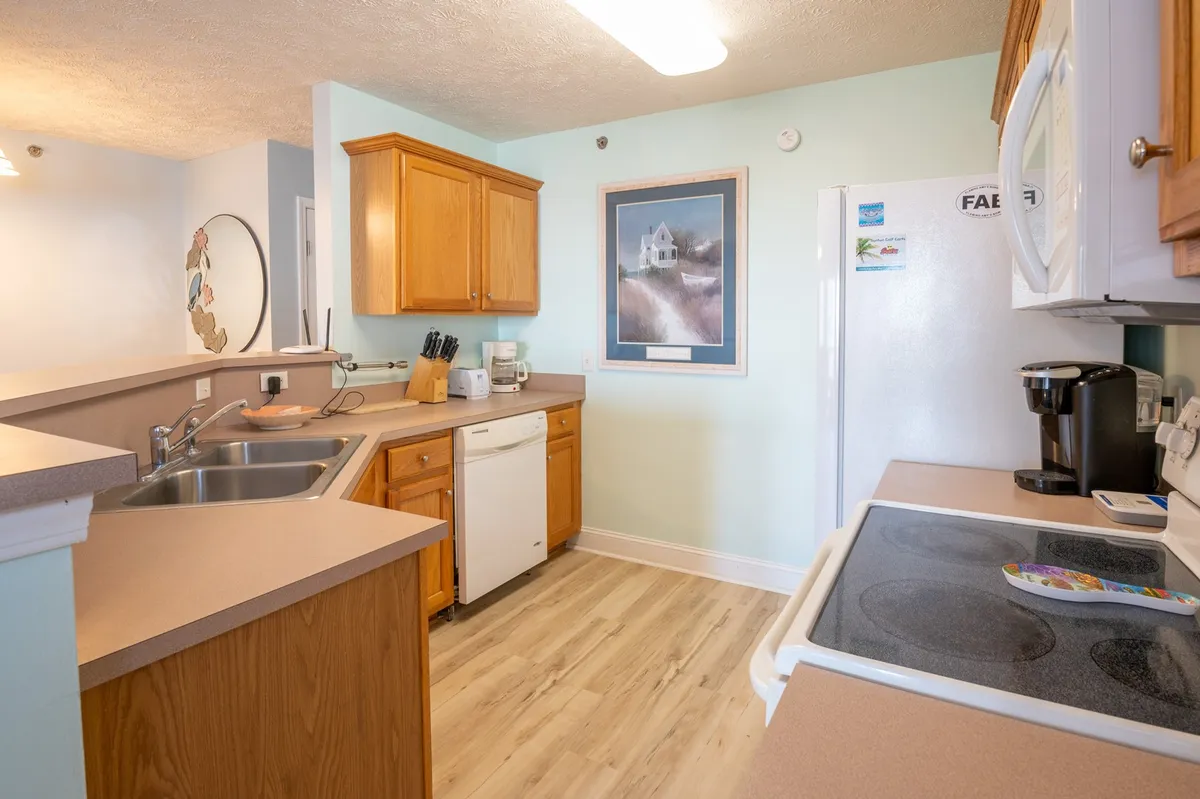 A bright and comfortable kitchen featuring wooden cabinets, modern appliances, and framed artwork. The space is designed for cooking, entertaining, and gathering, offering guests everything needed for self-catered meals.