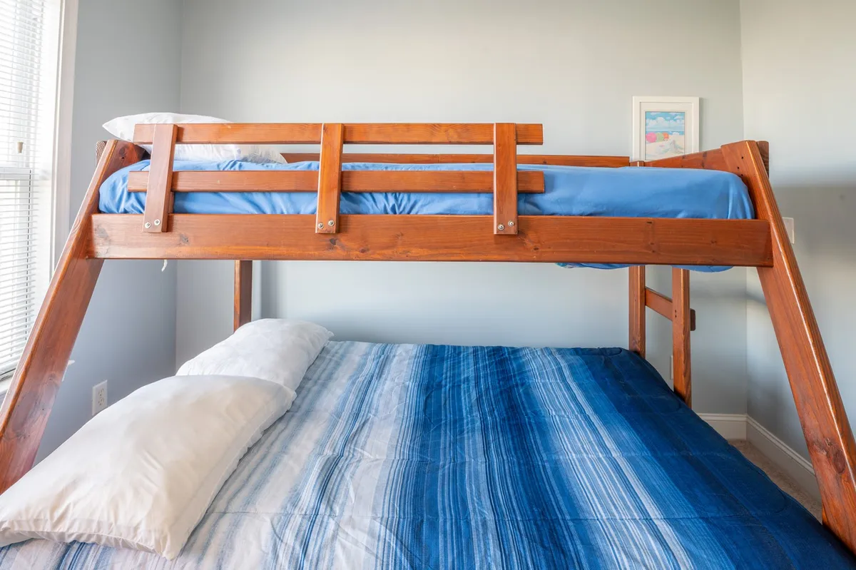 A playful lofted bedroom with a lower and upper bed, striped bedding, and a wooden frame. The scene evokes a sense of fun and relaxation—perfect for families or friends seeking a cozy retreat after a day of adventure.
